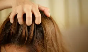 Main qui se gratte le cuir chevelu, une question que l'on se pose : pourquoi mes cheveux graissent vite ?