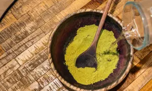 Préparation d'une pâte de henné. On verse de l'eau sur la poudre verte dans un bol en bois. Peut-on conserver une coloration ouverte ?