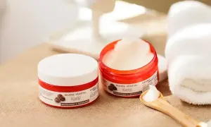 Deux pots de beurre de karité, parfaits pour les bienfaits cheveux. Une cuillère en bois en présente la texture onctueuse.