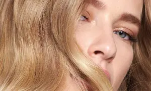Un gros plan sur le visage d'une femme aux cheveux blonds ondulés. Une question se pose : comment savoir si le blond me va ?
