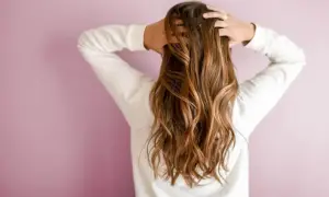 Une brune aux cheveux longs et ondulés, sublimés par un balayage caramel subtil qui capte la lumière.