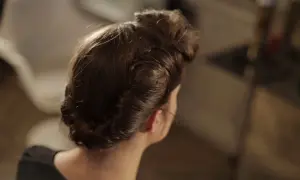 Coiffure année 50 élégante, avec des boucles et un chignon bas, rappelant le glamour d'une autre époque.