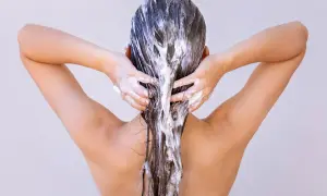 Femme appliquant un masque capillaire, se demandant combien de temps laisser poser un masque cheveux pour un soin optimal.