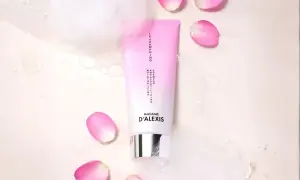 Tube de shampooing rose et blanc, entouré de pétales de rose et de bulles. Idéal pour espacer les shampoings et hydrater vos cheveux.