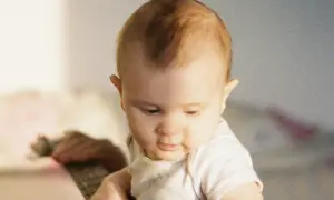 Un bébé au regard doux, ses premiers cheveux commencent à pousser, un moment précieux quand les cheveux de bébé poussent.