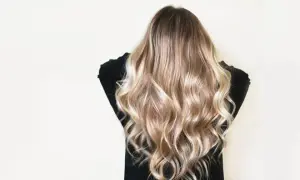 Cheveux châtain transformés en une cascade de mèches blondes lumineuses, un éclaircissement subtil pour un look naturel et ensoleillé.