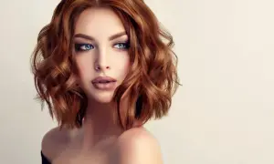 Une femme aux yeux bleus perçants et aux cheveux châtain clair ondulés, coiffés d'un brushing souple.