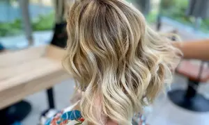 Chevelure blonde ondulée, parfaite pour comment cacher ses cheveux blancs. Les reflets subtils camouflent les premières mèches grises.
