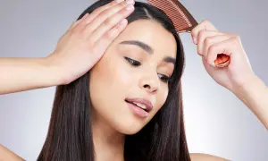 Une femme se peigne les cheveux, montrant comment enlever une raie de cheveux pour un look parfait.