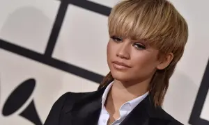 Zendaya arbore une coupe année 80 audacieuse, un mulet blond, avec un blazer noir et une chemise blanche.
