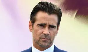 Colin Farrell arbore une coupe de cheveux homme mi long en arrière, un regard intense et un costume bleu.