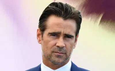 Colin Farrell arbore une coupe de cheveux homme mi long en arrière, un regard intense et un costume bleu.