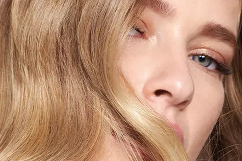 Un gros plan sur le visage d'une femme aux cheveux blonds ondulés. Une question se pose : comment savoir si le blond me va ?