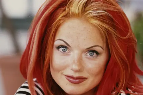 Un portrait de Geri Halliwell, ses cheveux roux flamboyants contrastent avec deux mèches blondes devant.
