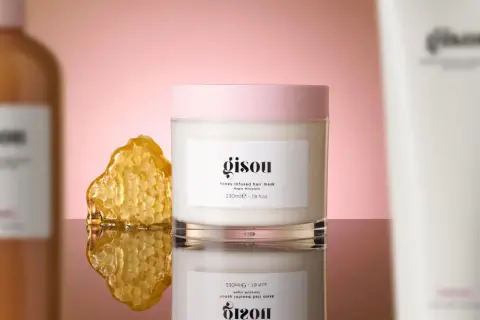 Masque cheveux Gisou infusé au miel, à utiliser avant ou après le shampoing, avec un morceau de nid d'abeille.