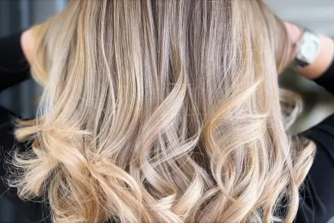 Chevelure brune sublimée par des mèches blondes polaires, créant un contraste subtil et lumineux.