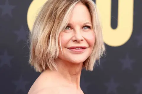 Une femme de 50 ans avec une coupe courte et dégradée, parfaite pour des cheveux fins et plats, rayonne sur le tapis rouge.