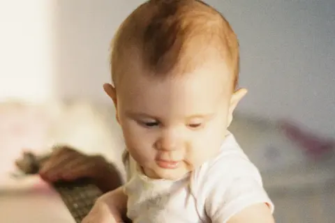 Un bébé au regard doux, ses premiers cheveux commencent à pousser, un moment précieux quand les cheveux de bébé poussent.
