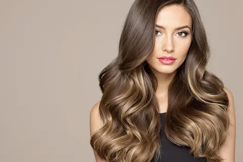 Magnifique balayage meche blonde sur cheveux noir, des ondulations douces et un regard captivant.