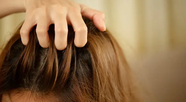 Main qui se gratte le cuir chevelu, une question que l'on se pose : pourquoi mes cheveux graissent vite ?