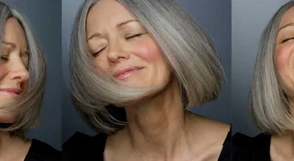 Une femme de 60 ans au visage ovale arbore une coupe de cheveux courte et grisonnante, exprimant joie et sérénité.