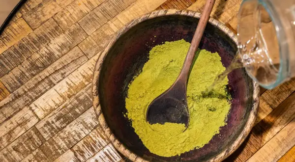 Préparation d'une pâte de henné. On verse de l'eau sur la poudre verte dans un bol en bois. Peut-on conserver une coloration ouverte ?