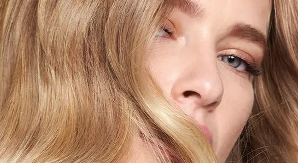 Un gros plan sur le visage d'une femme aux cheveux blonds ondulés. Une question se pose : comment savoir si le blond me va ?