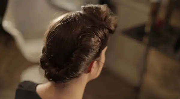 Coiffure année 50 élégante, avec des boucles et un chignon bas, rappelant le glamour d'une autre époque.