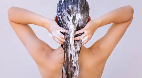 Femme appliquant un masque capillaire, se demandant combien de temps laisser poser un masque cheveux pour un soin optimal.