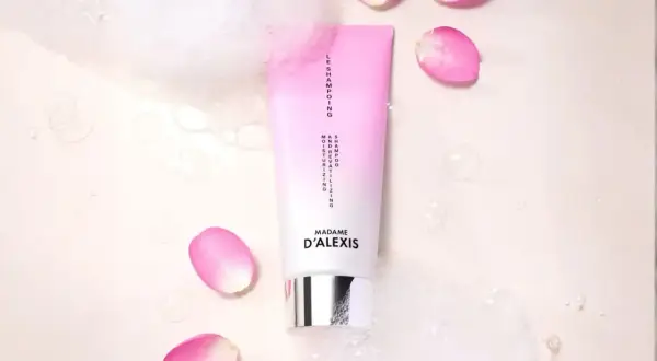 Tube de shampooing rose et blanc, entouré de pétales de rose et de bulles. Idéal pour espacer les shampoings et hydrater vos cheveux.