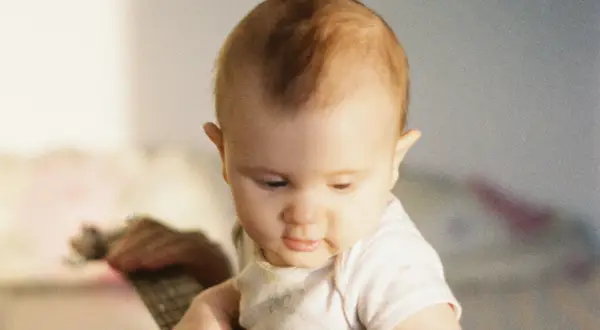 Un bébé au regard doux, ses premiers cheveux commencent à pousser, un moment précieux quand les cheveux de bébé poussent.