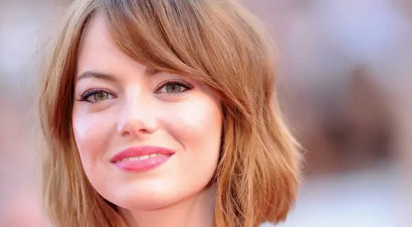 Emma Stone, avec sa coupe de cheveux courte et ondulée, met en valeur son visage rond et ses grands yeux verts.