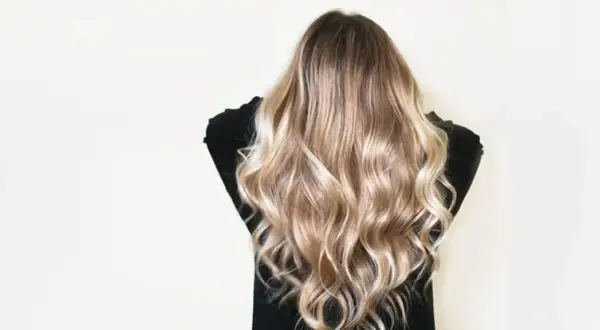 Cheveux châtain transformés en une cascade de mèches blondes lumineuses, un éclaircissement subtil pour un look naturel et ensoleillé.