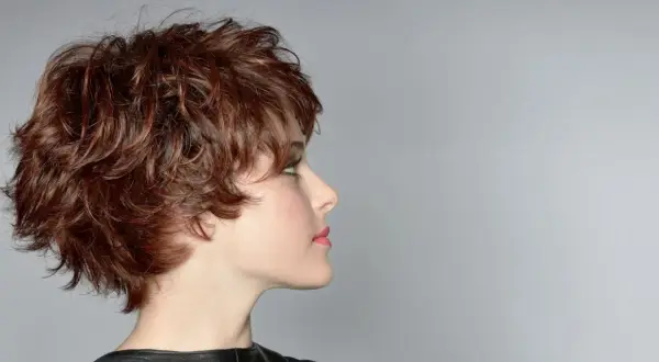 Profil d'une femme avec une coupe courte aux cheveux épais et volumineux, arborant un effet décoiffé naturel et moderne.