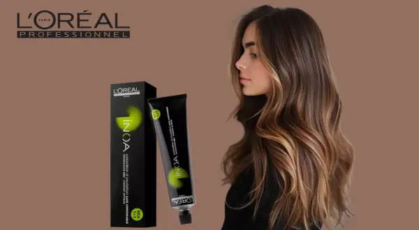 Une femme aux cheveux bruns et blonds, avec une boîte et un tube de coloration INOA L'Oréal. Le temps de pause parfait pour une couleur éclatante.