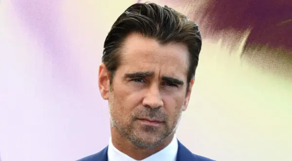 Colin Farrell arbore une coupe de cheveux homme mi long en arrière, un regard intense et un costume bleu.