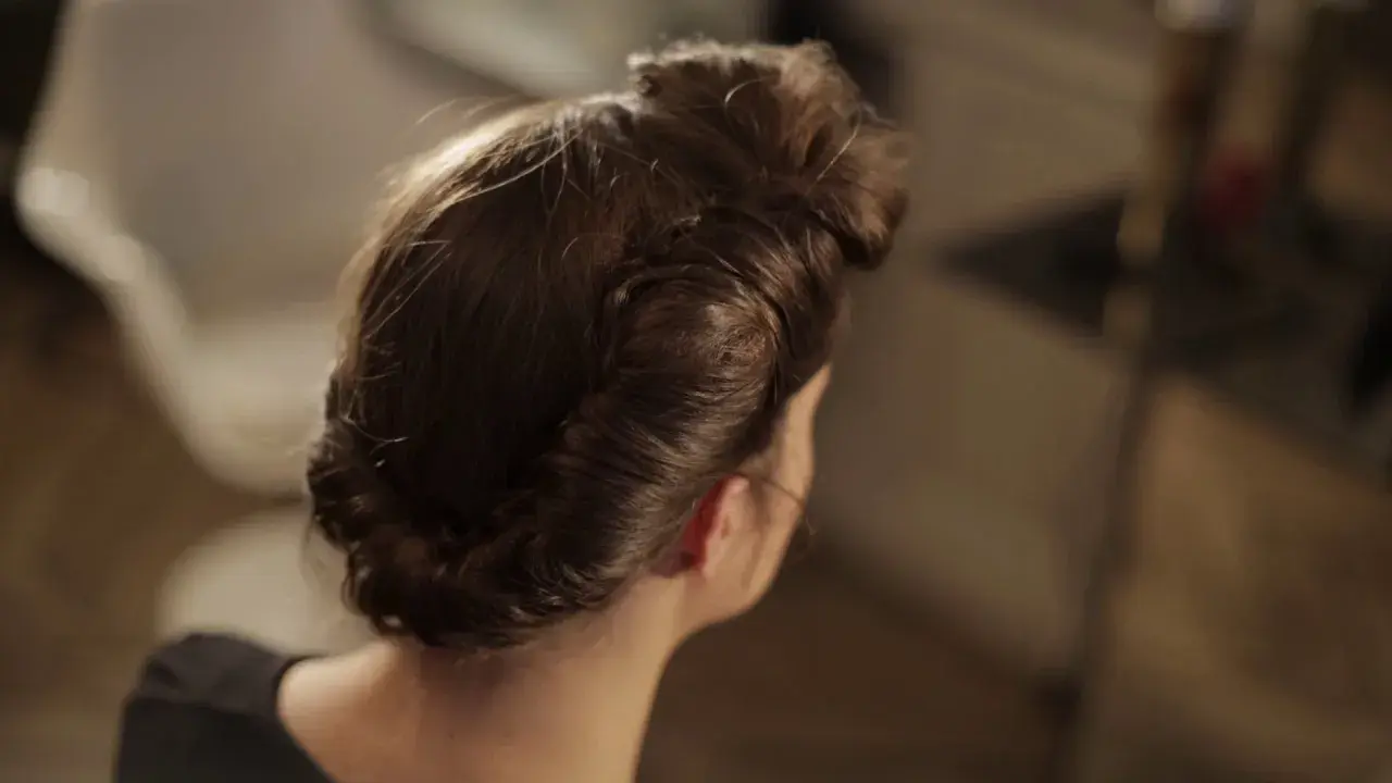Coiffure année 50 élégante, avec des boucles et un chignon bas, rappelant le glamour d'une autre époque.