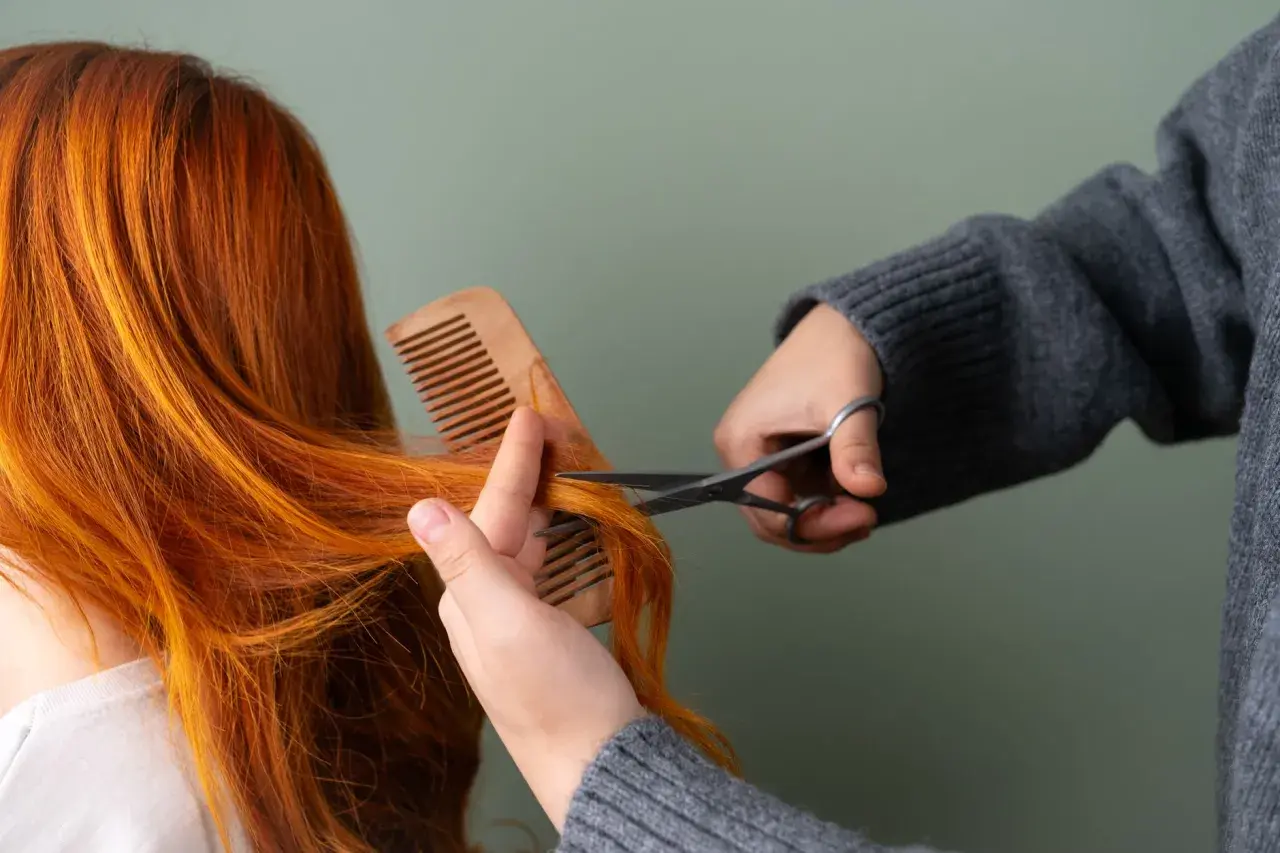 Une personne se coupe les cheveux roux avec des ciseaux, comme si elle se coupait les cheveux avec la lune.