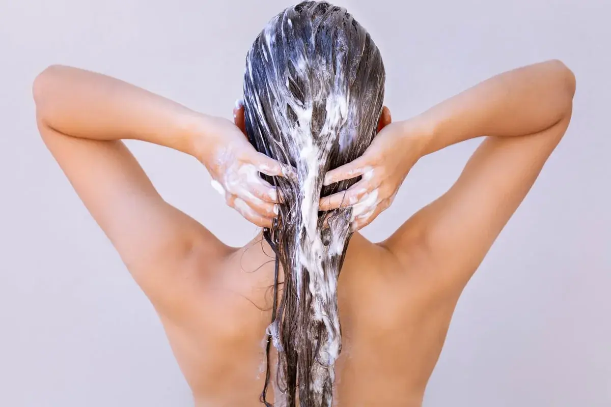 Femme appliquant un masque capillaire, se demandant combien de temps laisser poser un masque cheveux pour un soin optimal.