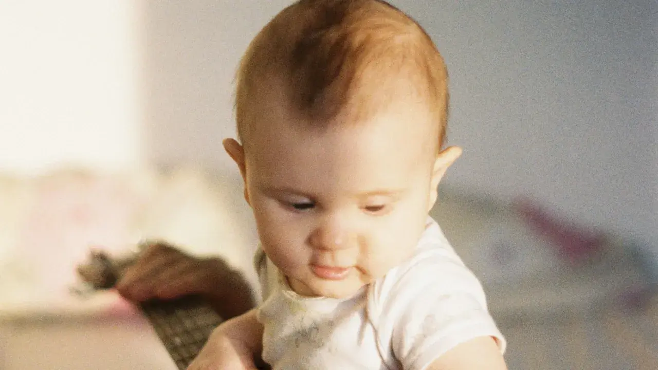 Un bébé au regard doux, ses premiers cheveux commencent à pousser, un moment précieux quand les cheveux de bébé poussent.