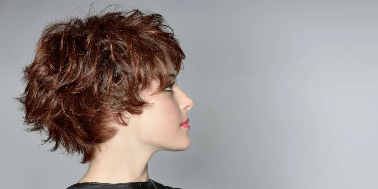 Profil d'une femme avec une coupe courte, cheveux &eacute;pais et volumineux, arborant un effet d&eacute;coiff&eacute; naturel et moderne.