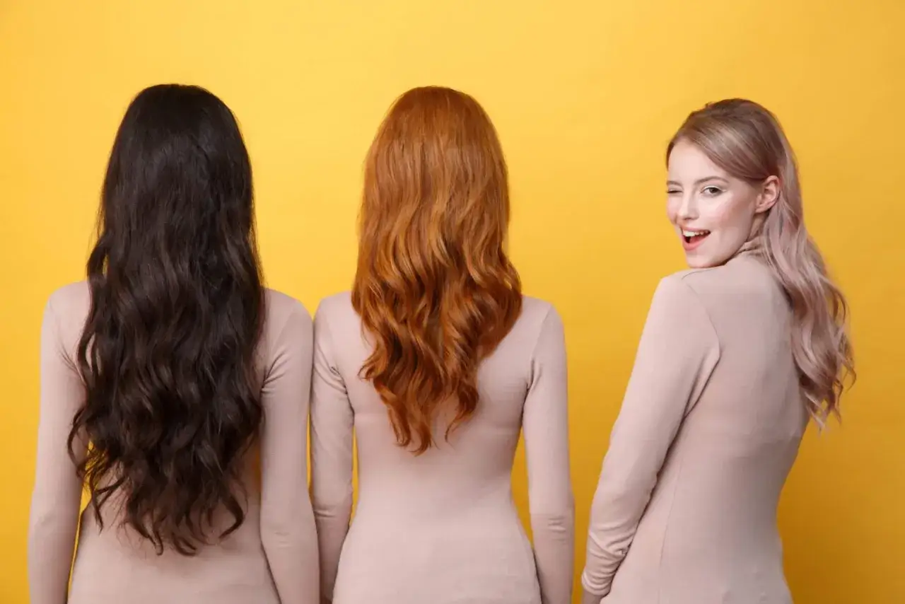 Trois femmes, une aux cheveux bruns, une rousse et une blonde, posent sur fond jaune. La colorim&eacute;trie couleur cheveux est mise en avant.