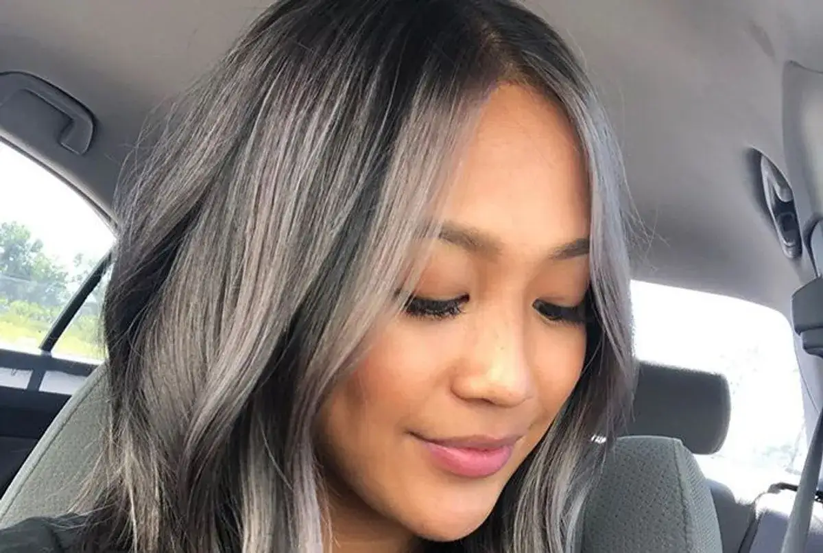 Une femme avec des cheveux mi-longs aux reflets gris et noirs, un parfait transition grey blending.