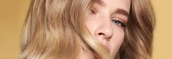 Un gros plan sur le visage d'une femme aux cheveux blonds ondulés. Une question se pose : comment savoir si le blond me va ?