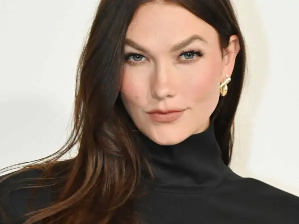 Une femme aux cheveux bruns foncés arbore une coloration claire subtile, sans décoloration visible, rehaussée par un col roulé noir et des boucles d'oreilles dorées.