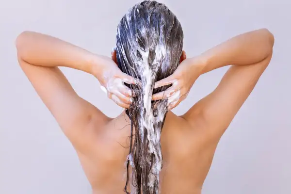 Femme appliquant un masque capillaire, se demandant combien de temps laisser poser un masque cheveux pour un soin optimal.