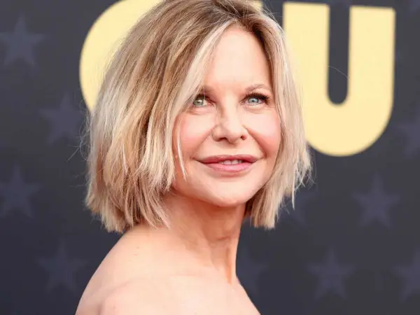 Une femme de 50 ans avec une coupe courte et dégradée, parfaite pour des cheveux fins et plats, rayonne sur le tapis rouge.