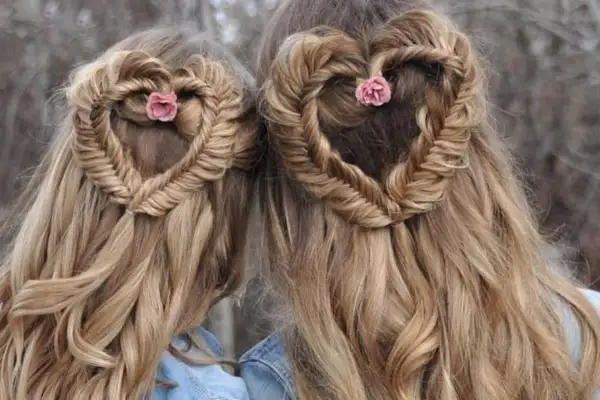 Deux coiffures femme cheveux long en forme de cœur tressé, ornées de petites fleurs roses.