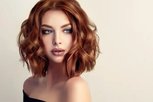 Une femme aux yeux bleus perçants et aux cheveux châtain clair ondulés, coiffés d'un brushing souple.