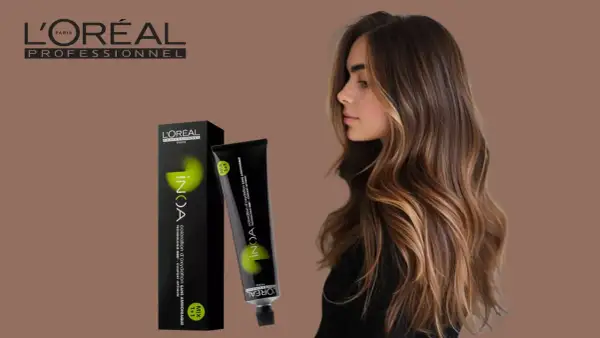 Une femme aux cheveux bruns et blonds, avec une boîte et un tube de coloration INOA L'Oréal. Le temps de pause parfait pour une couleur éclatante.